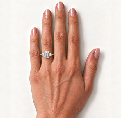 Emerald-cut diamond three-stone ring in yellow gold on the hand