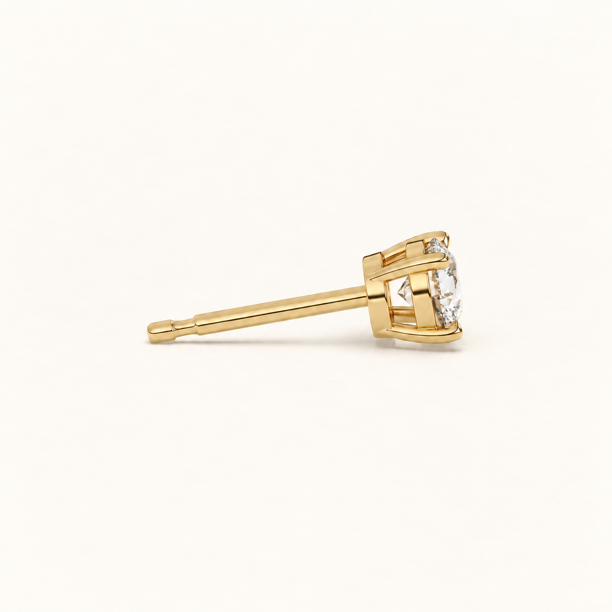 Round brilliant diamond studs in yellow gold, side view on warm ivory