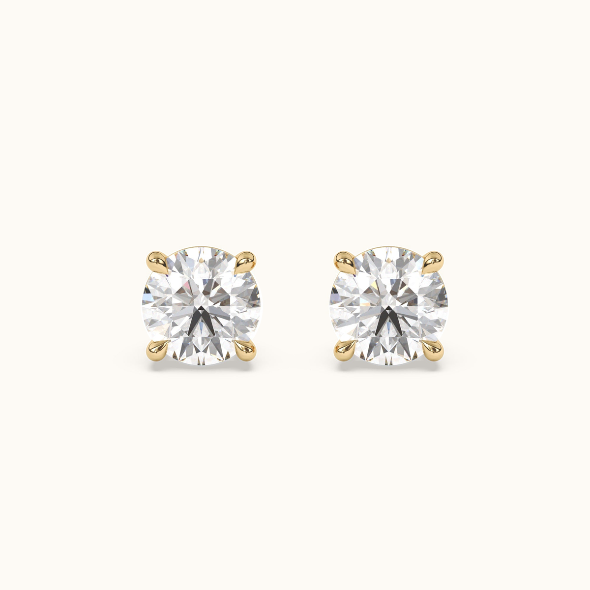 Round brilliant diamond studs in yellow gold, front pair view on warm ivory