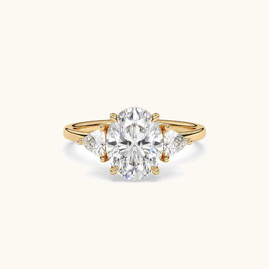 Front view of an oval diamond three-stone ring in yellow gold with trillion diamond shoulders